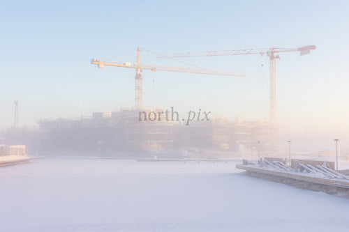Construction cranes over frozen harbor in winter morning