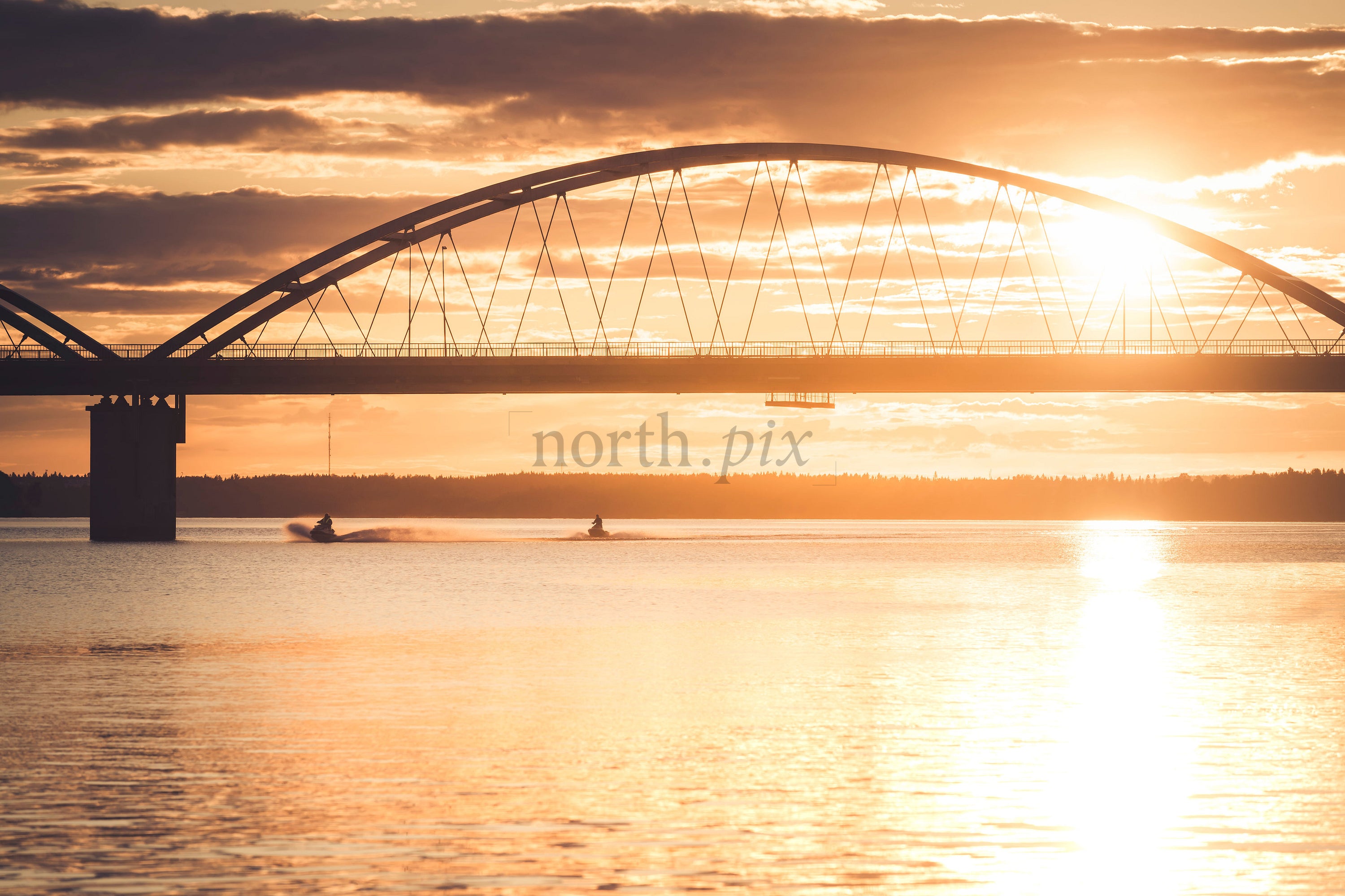 Arch bridge over water at sunset