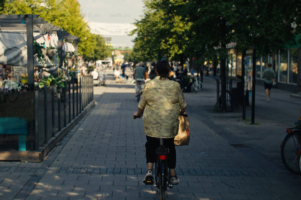 Cyclist riding through Luleå city center with outdoor cafes and busy pedestrian street