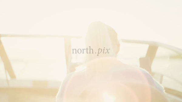 Woman Steering Boat in the Luleå Archipelago, Sweden. Summer Sunshine, Lens Flare. Baltic Sea. POV