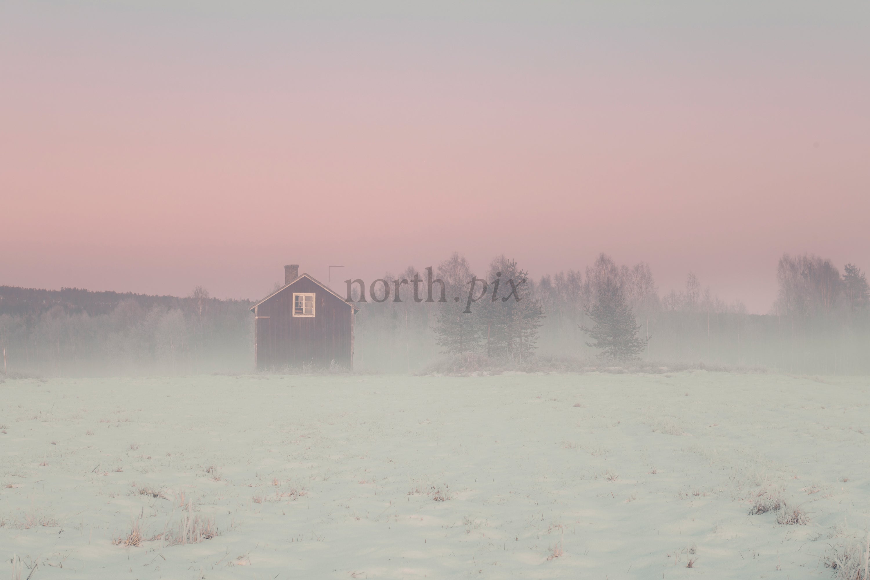 Small red house in snowy field at sunrise