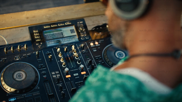 DJ mixing music on controller outdoors at sunset in Luleå