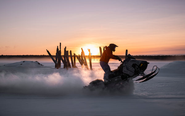Snowmobile rider on a frozen lake at sunset