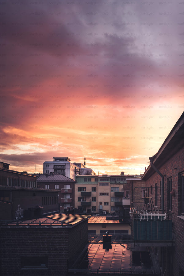 Rooftops and apartment buildings under a sunset sky