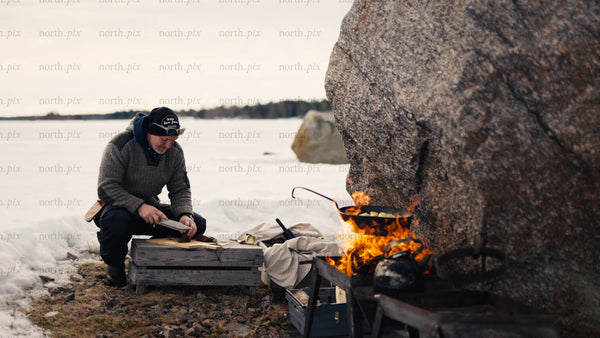 Man cooking on open fire, winter day in Luleå archipelago