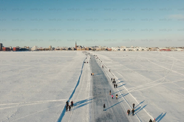 Snowy Luleå city center aerial view of frozen lake path and people walking