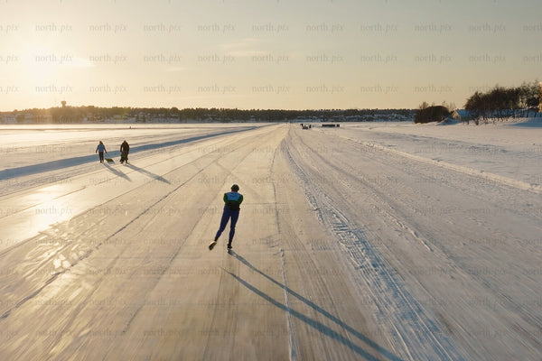 Ice skating along a snowy lake at sunset in Luleå city center, winter scene