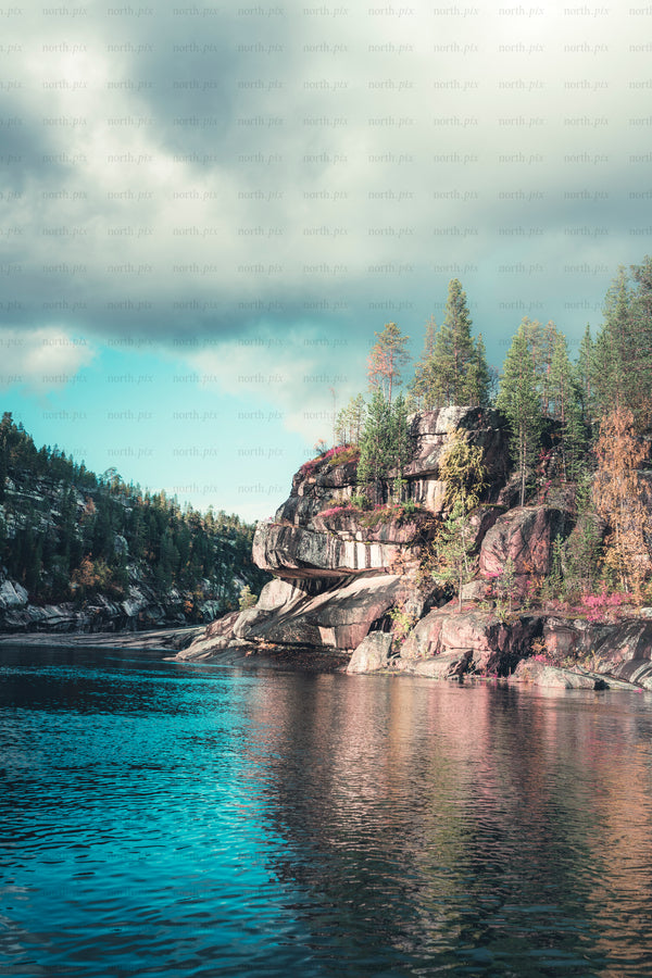 Jokkmokk - rocky lakeshore cliff with trees and reflections