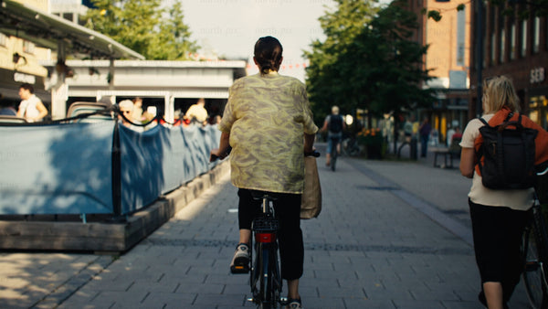 Woman on bicycle in Luleå city street during sunny summer day