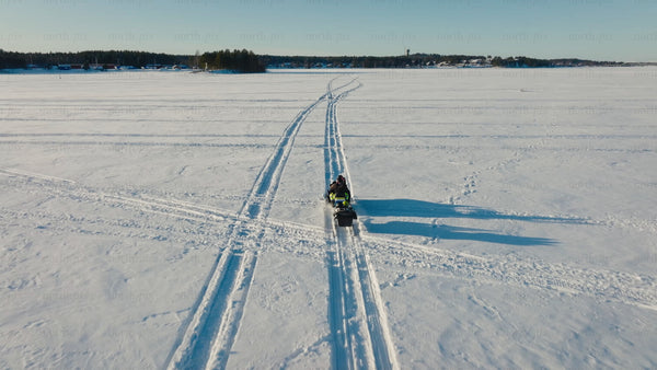 Snowmobile on frozen lake in Luleå – aerial view, sunny winter day