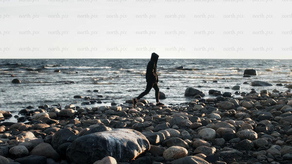 Lone person walks along rocky beach in Luleå archipelago during summer evening