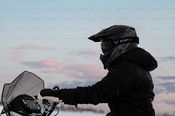 Snowmobile rider in winter dusk wearing helmet