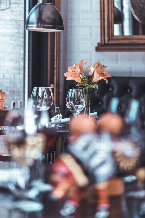 Table setting with lilies and wine glasses in restaurant