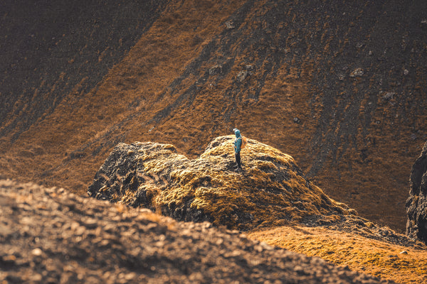 Hiker standing on mossy rock outcrop on hillside