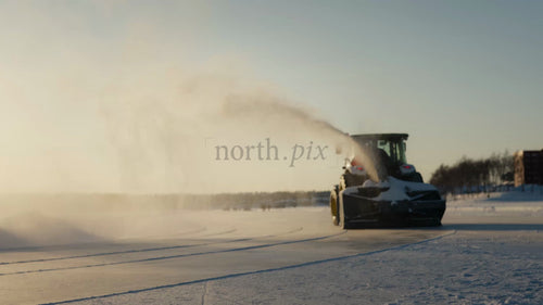 Snöslunga och traktor röjer frusen sjö i Luleå, Sverige, på en ljus vinterdag.