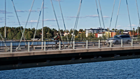 Cyclist on Bridge in Lulea, Sweden on a Sunny Summer Day with Cars and Scenic View