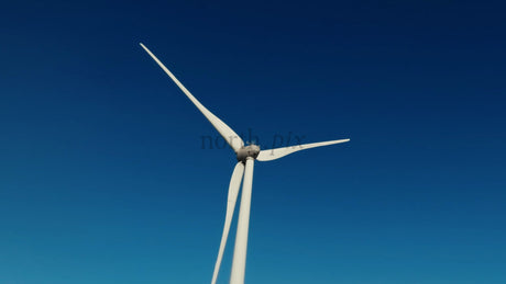 Wind Turbine Rotating Against a Clear Blue Sky in a Winter Landscape