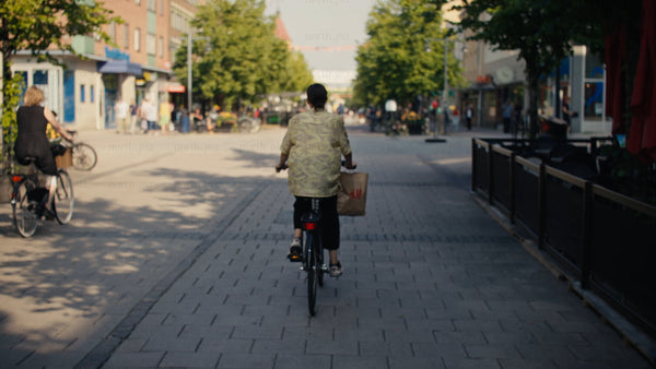 Woman cycles down shopping street in Luleå, on a sunny summer day