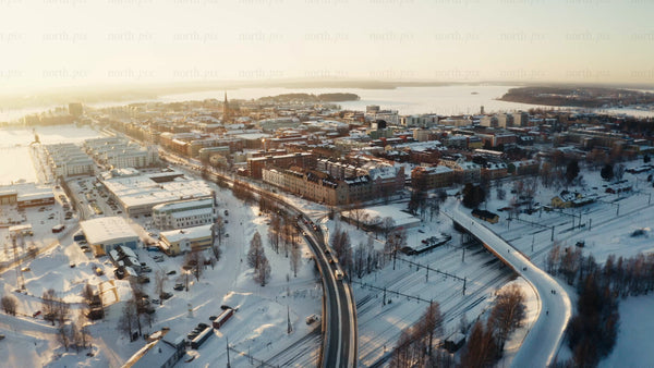 Winter sunset over Luleå: Aerial view of city center with snow, roads, and railway