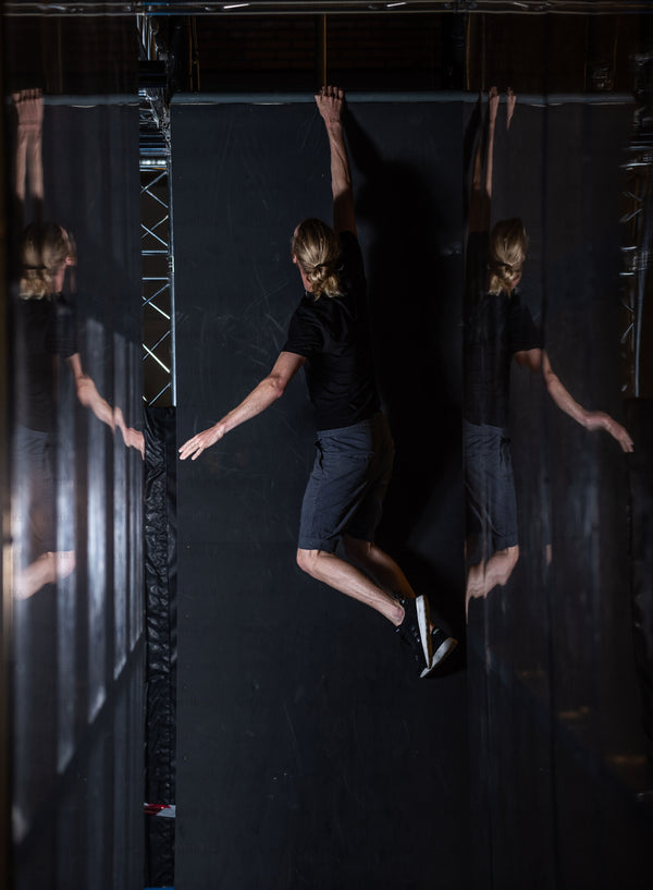 Person hanging from indoor wall with mirrored panels