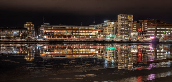Riverfront buildings reflected on icy water at night