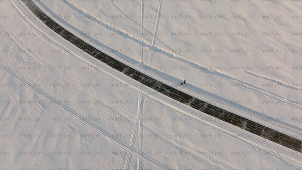 Aerial view of person walking dog on snowy road in winter landscape, Luleå
