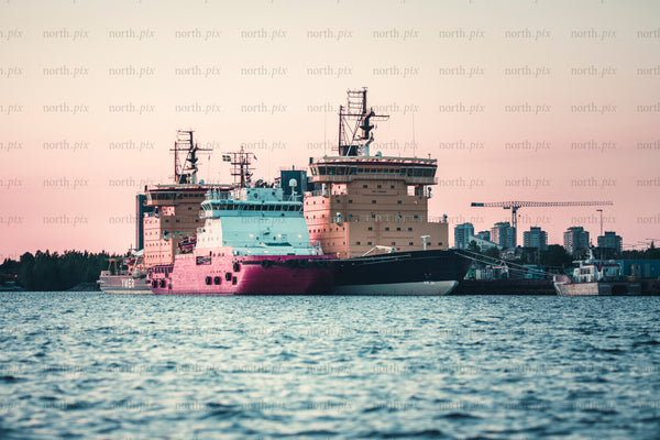 Ships docked at harbor at sunset