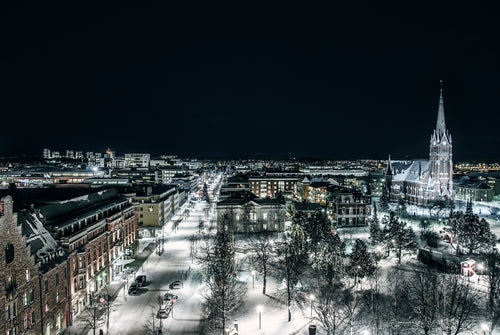 Flygfoto i mörker över snötäckt stad med kyrka