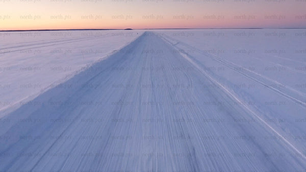 Driving on ice road at sunset in Luleå archipelago - aerial drone view