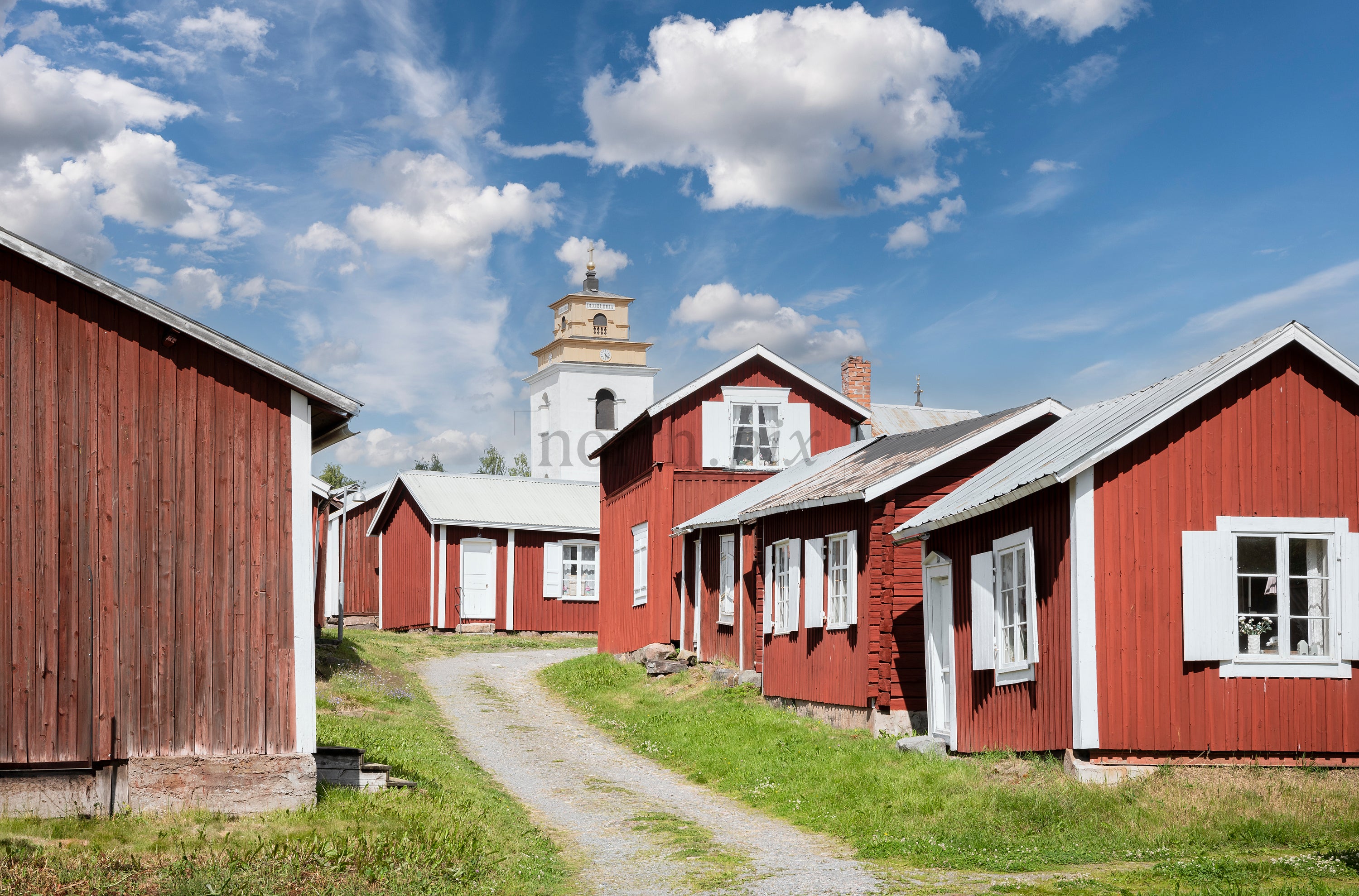 Red wooden houses with church tower in summer