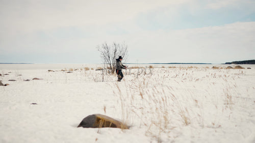 Man går genom snötäckt fält vid fruset Östersjön i Luleå, Sverige