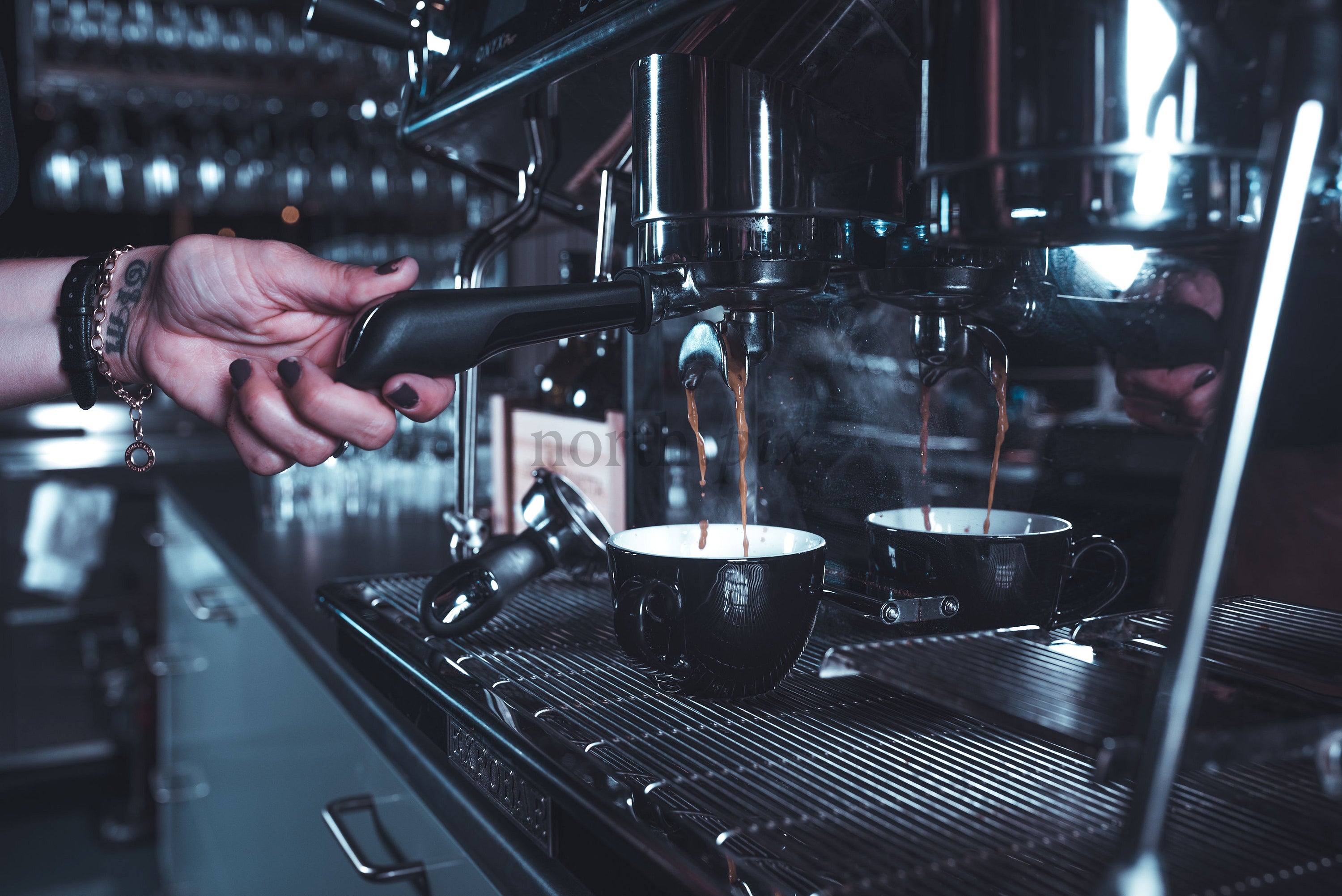 Barista pulling espresso shots at a commercial espresso machine