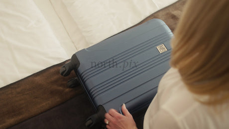 Woman Unpacking Suitcase in Stylish Hotel Room After Arriving in Lulea