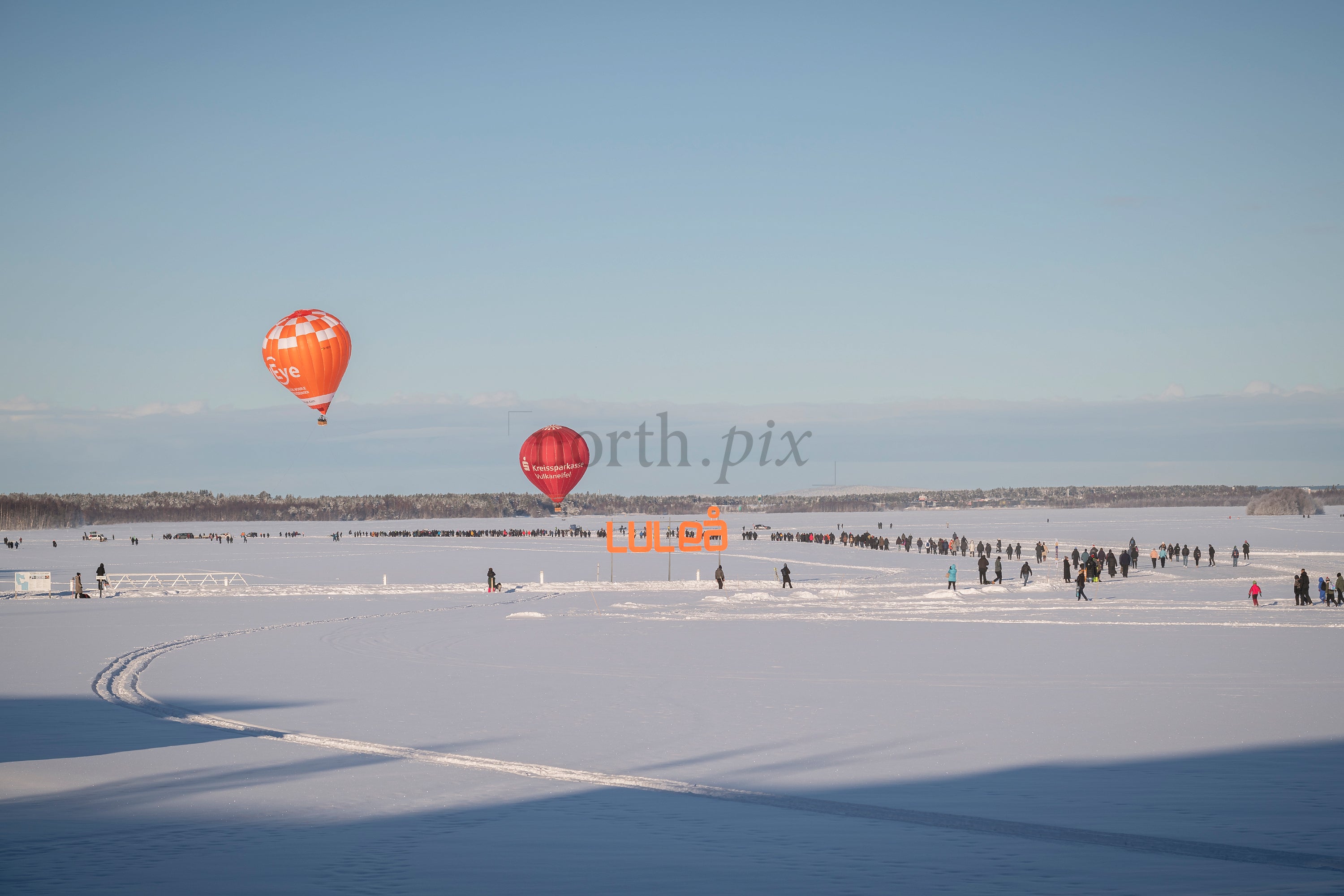 Hot Air Balloons Over Snowy Frozen Lake With Crowd And Luleå Winter Landscape