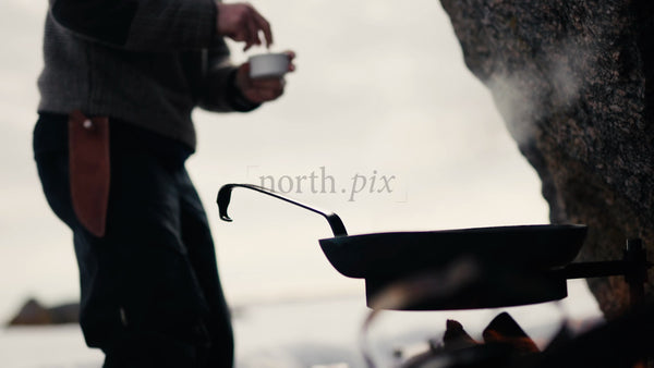 Man Cooking on Open Fire on Winter Beach in Lulea Archipelago, Sweden