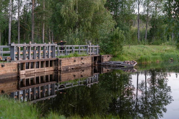 Wooden sluice and small boat by river at dusk