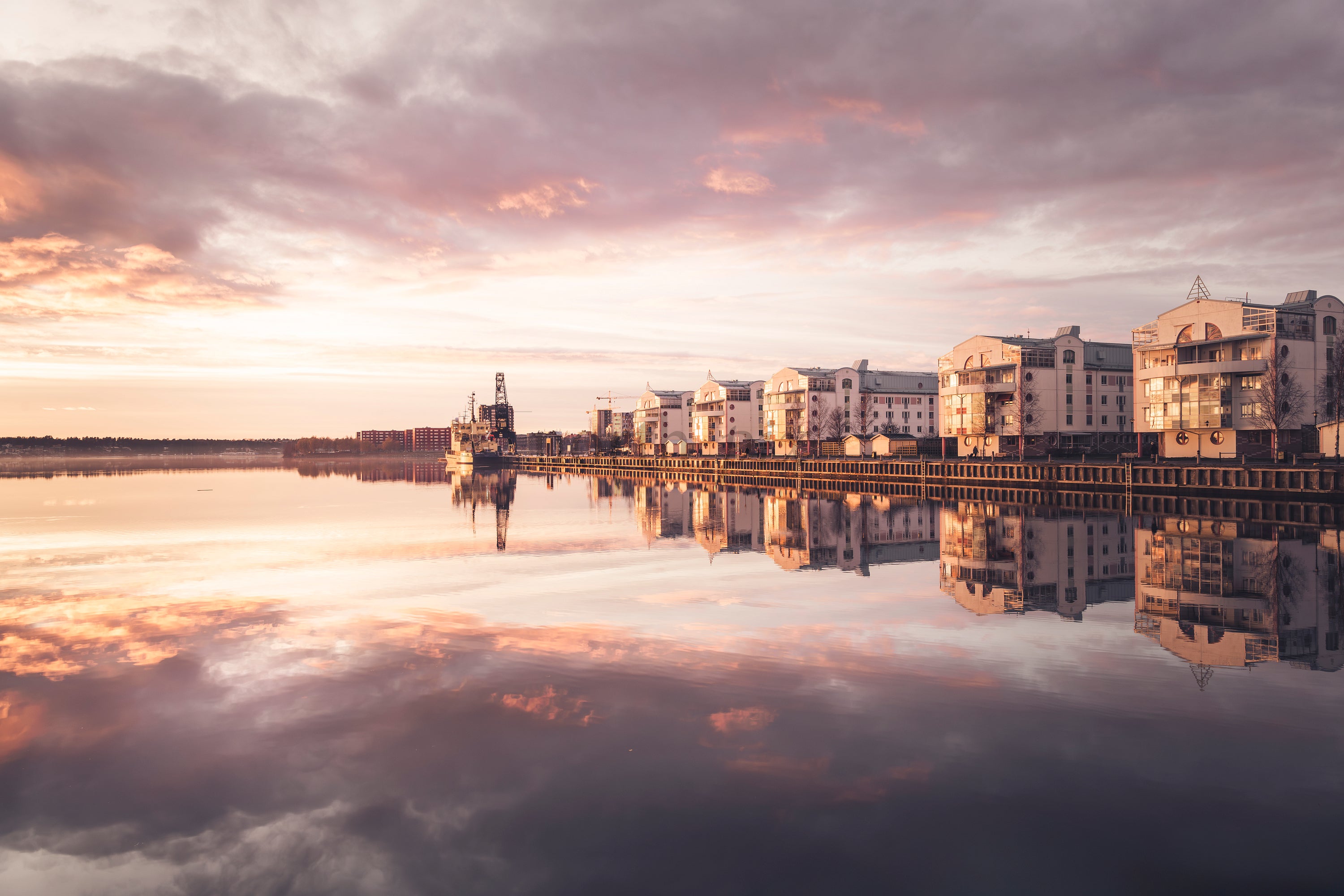 Waterfront apartment buildings "Tuttifrutti" reflected in calm sunset water