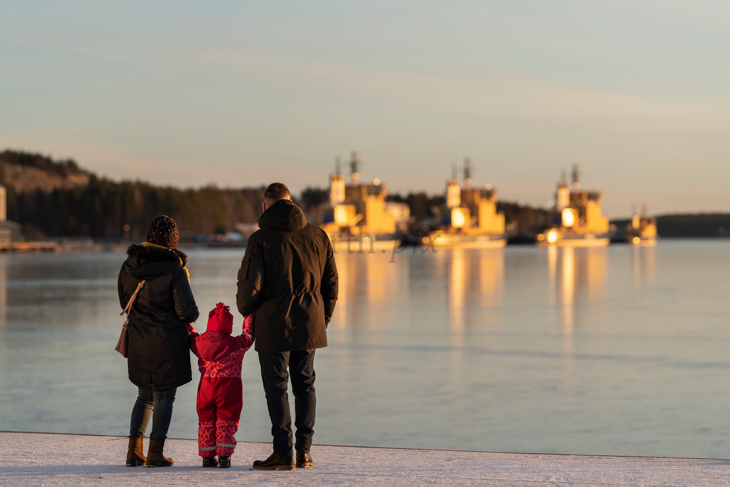 Family on frozen waterfront at sunset