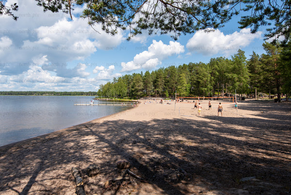 People playing volleyball on a sandy lake beach in summer