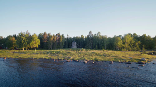 Sommarkvällsdrönvy av väderkvarn på skogsklädd ö i Luleå skärgård, Sverige