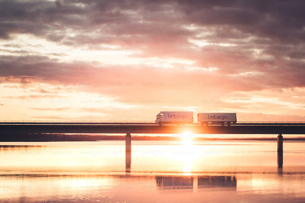 Cargo trucks on bridge at sunrise
