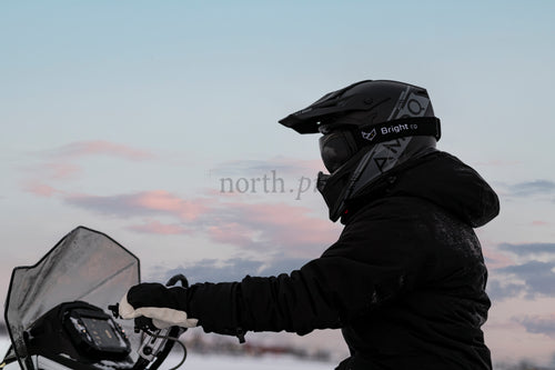 Snowmobile rider in winter dusk wearing helmet