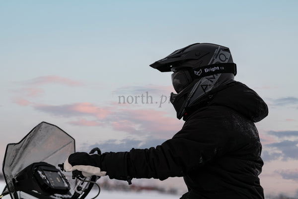 Snowmobile rider in winter dusk wearing helmet