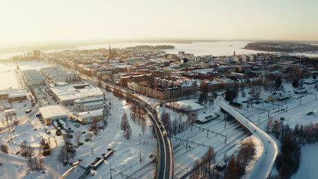 Winter Sunset Over Luleå: Aerial View of City Center with Snow, Roads, and Railway
