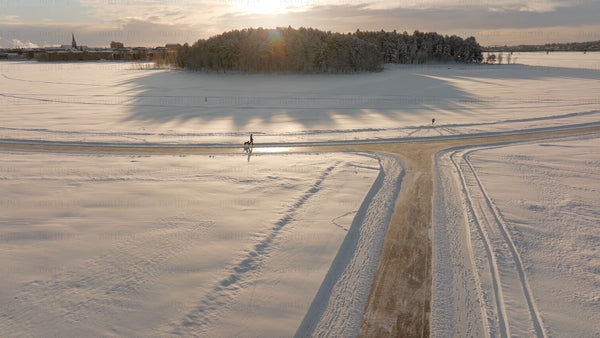 Winter Wonderland in Lulea, Sweden: Aerial View of Snowy Landscape at Sunset with Dog Walker