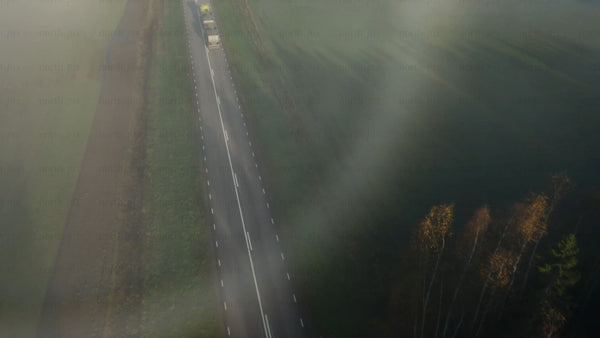 Misty road through rural countryside with autumn forest and fields