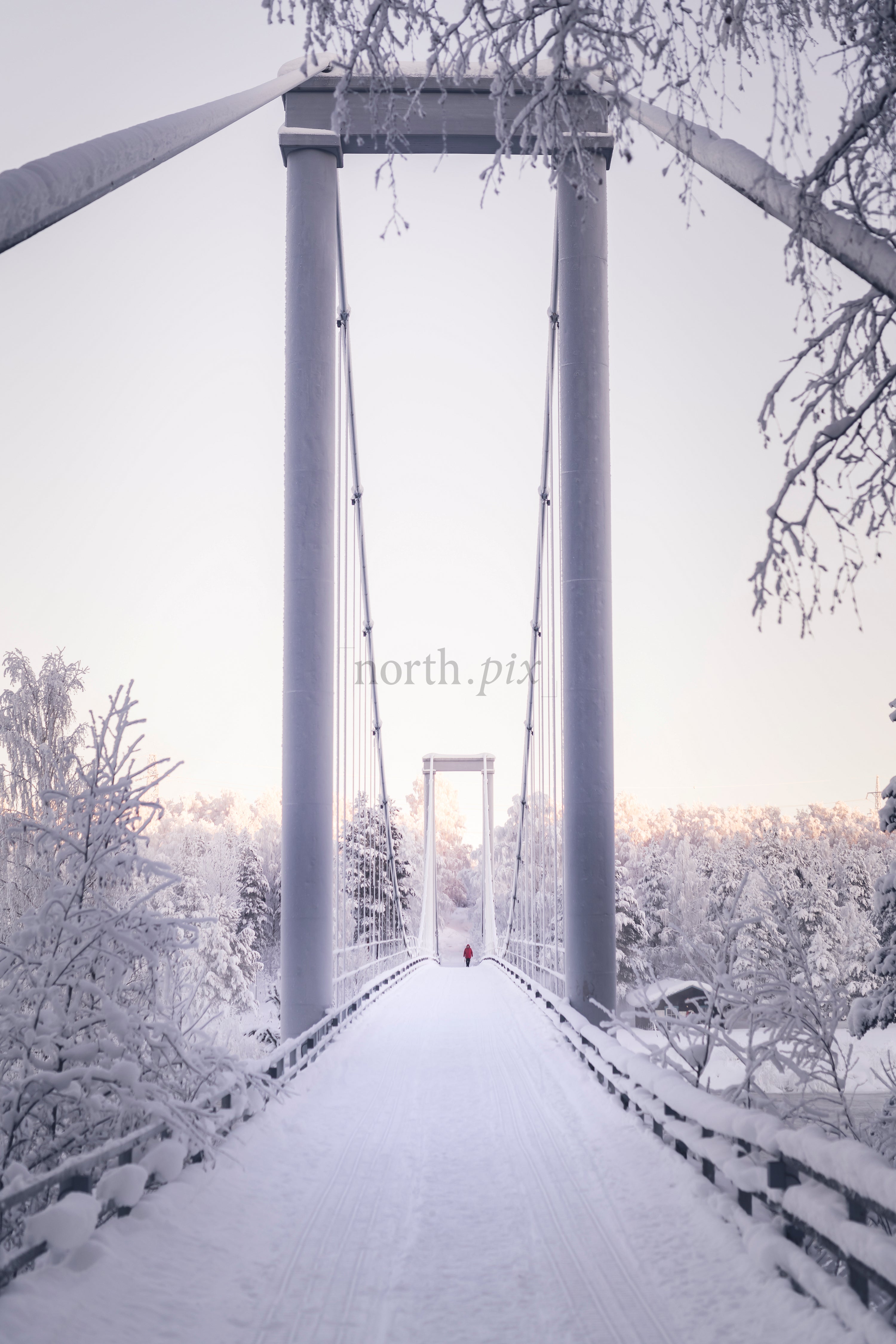 Pedestrian suspension bridge covered in snow at dawn