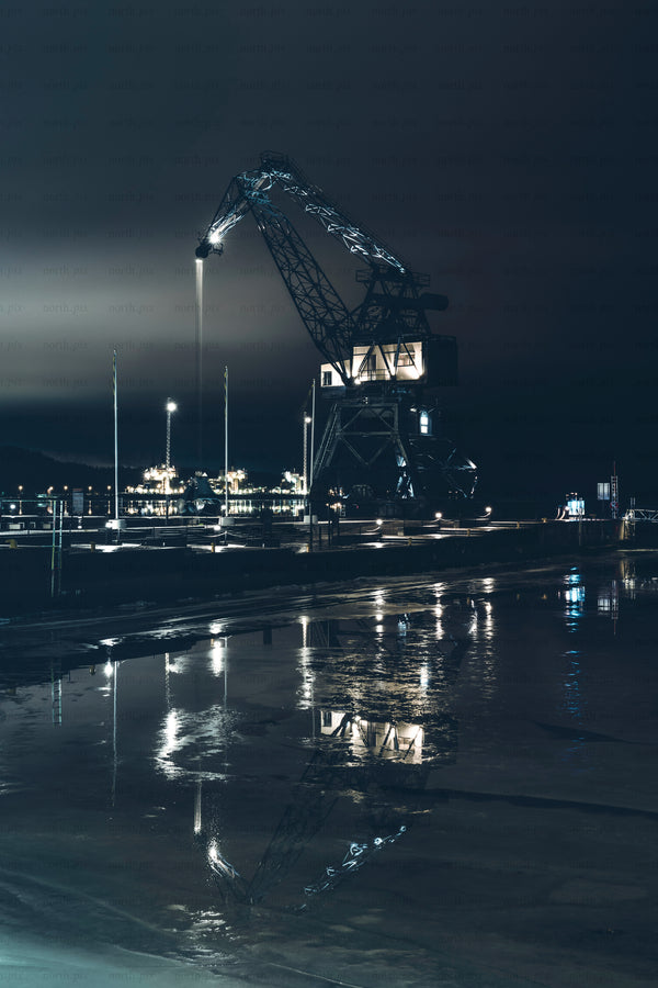 Industrial harbor crane at night with water reflection