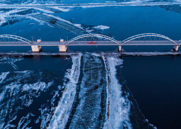 Aerial view of a winter bridge over frozen waters during blue hour
