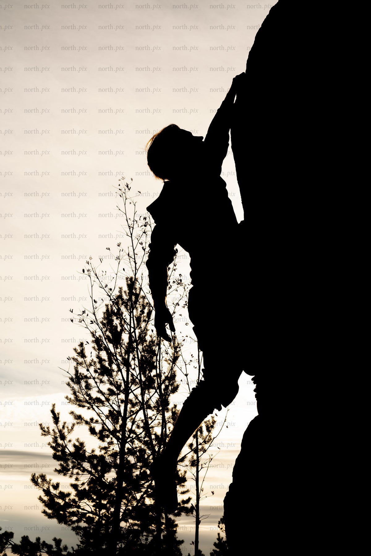 Silhouette of climber on rock face at sunset